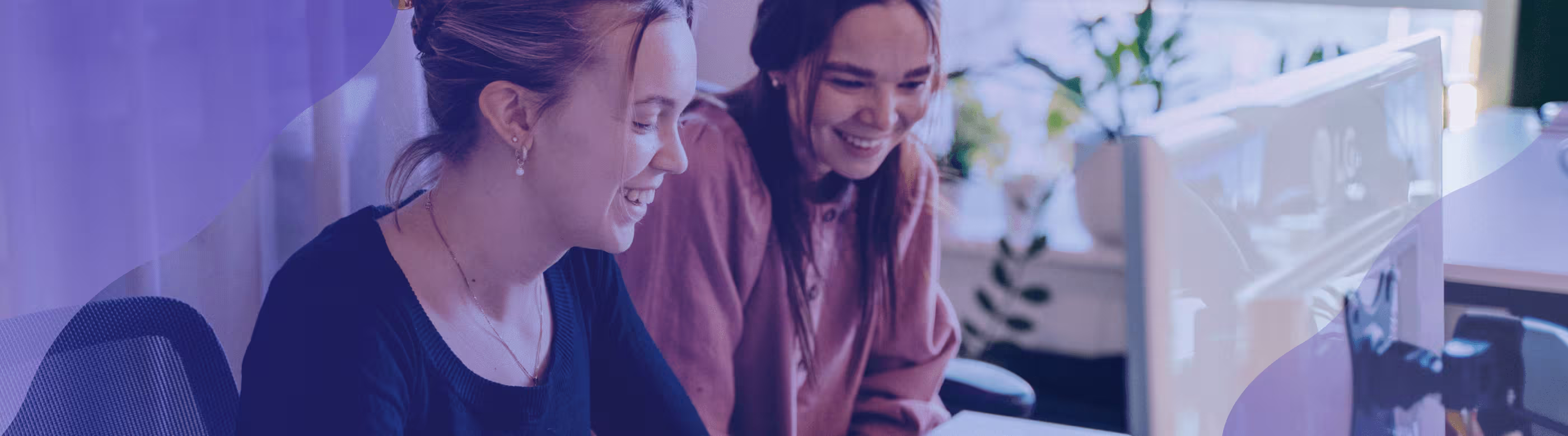 Two women smiling and looking at a monitor