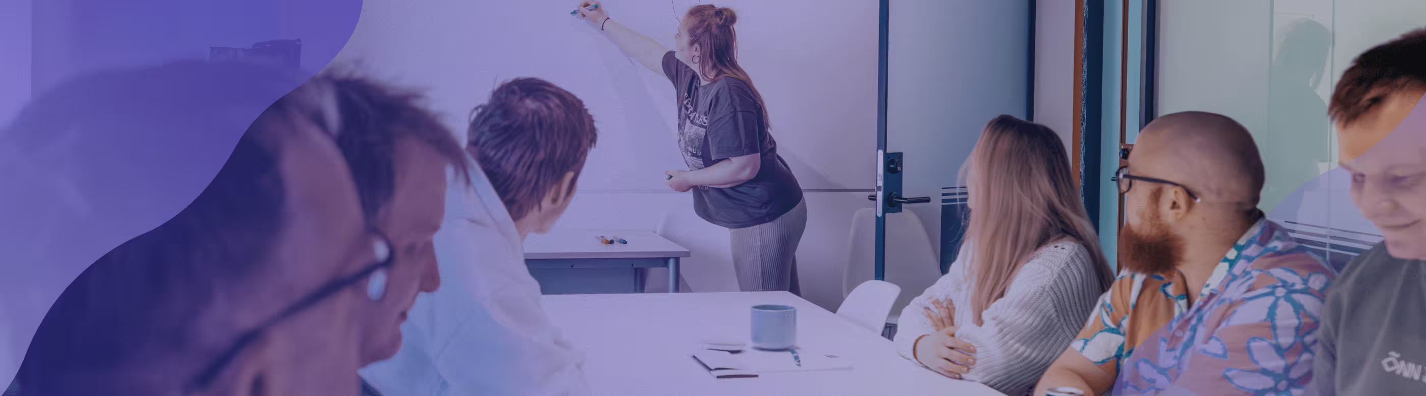 People in a meeting looking at a whiteboard